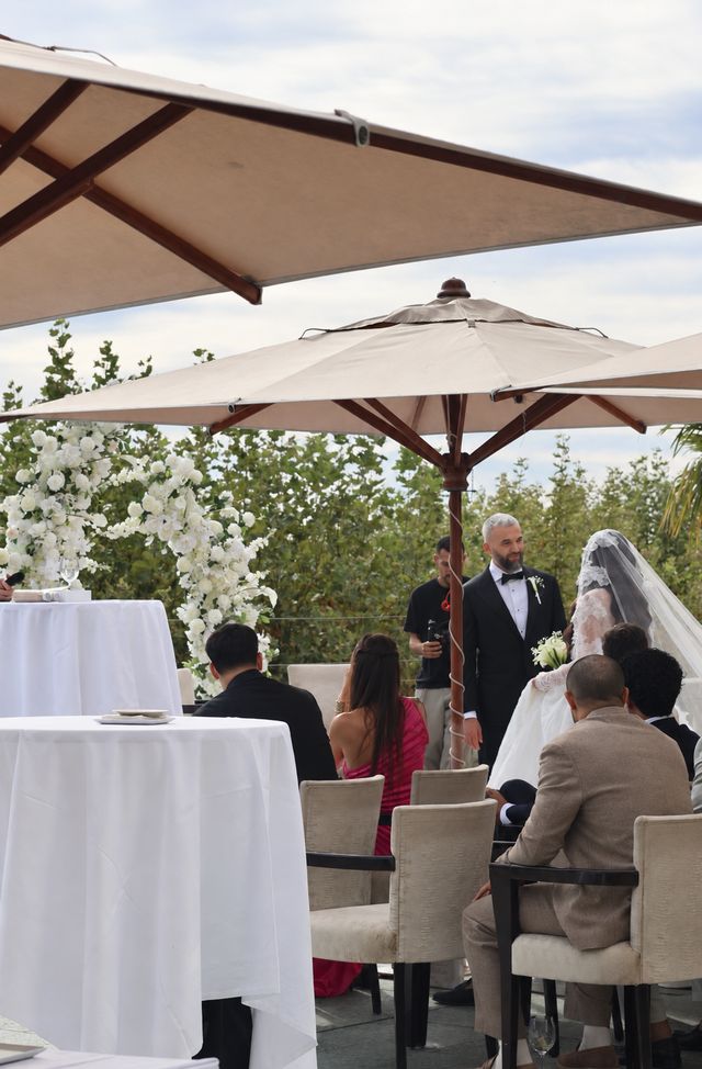 Cérémonie de mariage en terrasse sous les parasols, décor floral blanc