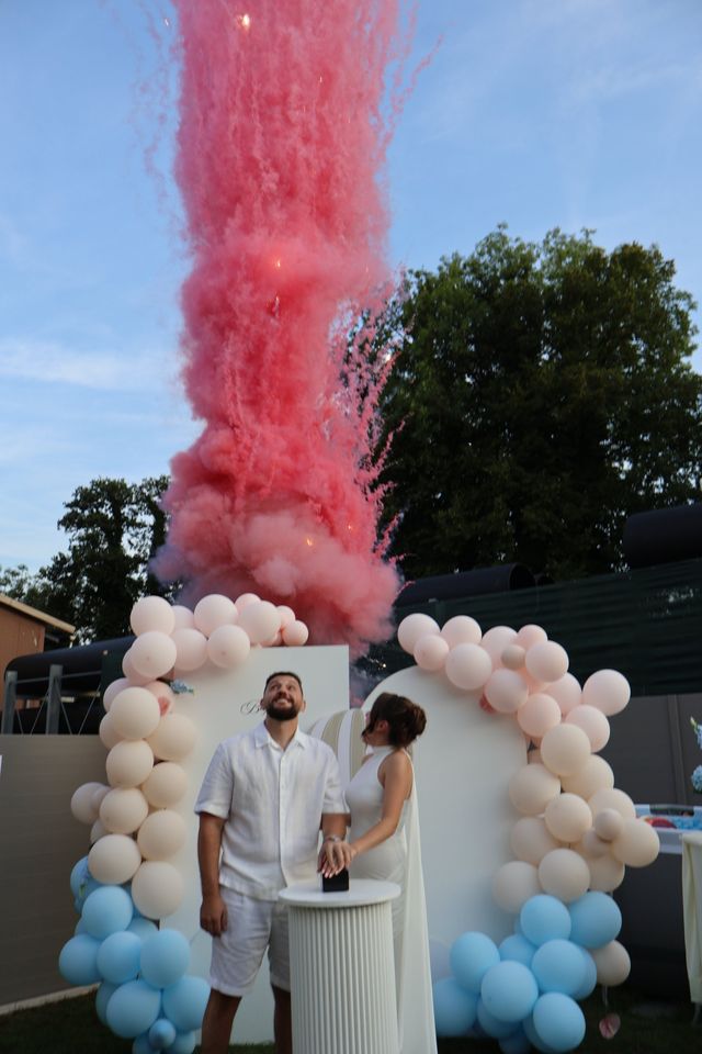 Fumée rose lors d'une révélation du sexe du bébé, devant une arche de ballons roses et bleus