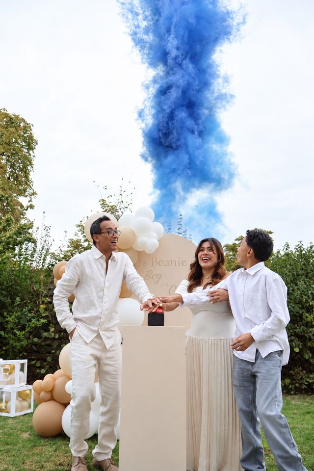 Famille appuyant sur le bouton de la révélation, avec une fumée bleue dans le ciel