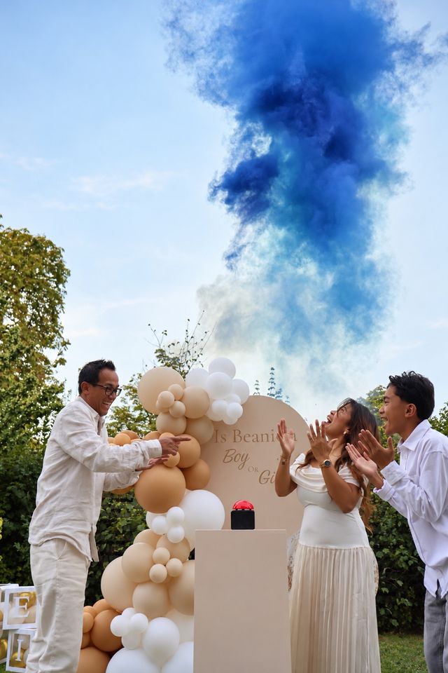 Fumée bleue pour une révélation du sexe du bébé, famille qui applaudit près d'une arche de ballons beiges