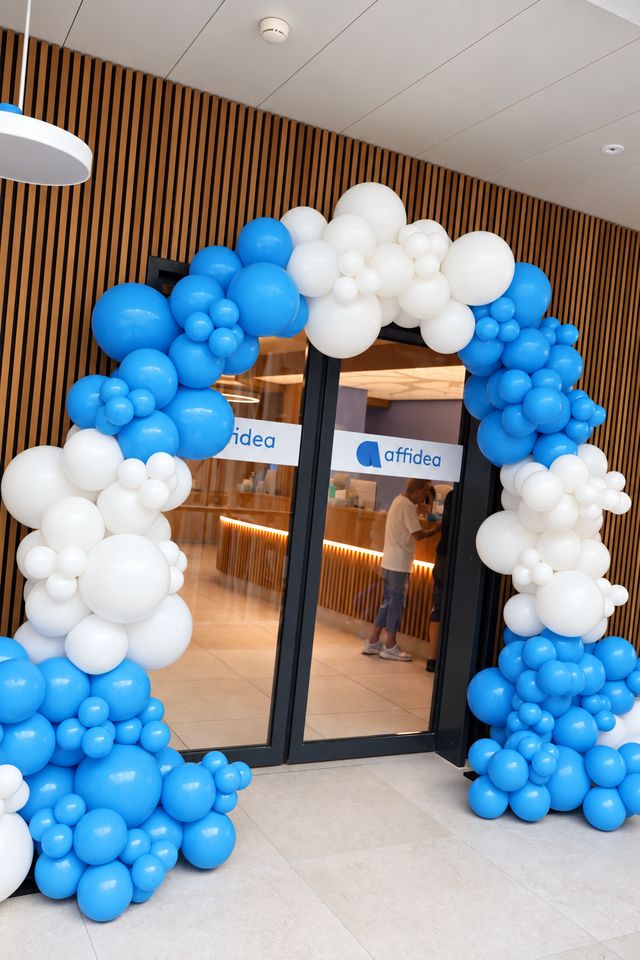 Arche de ballons bleus et blancs à l'entrée d'un établissement Affidea